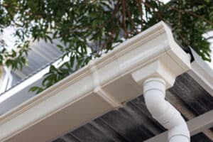 white plastic rain gutter of roof of house. vinyl rain gutter and downpipe.